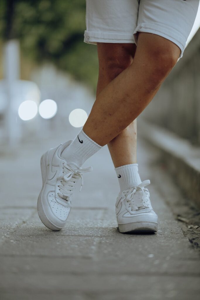 A stylish close-up of white trainers and legs in shorts, outdoors.