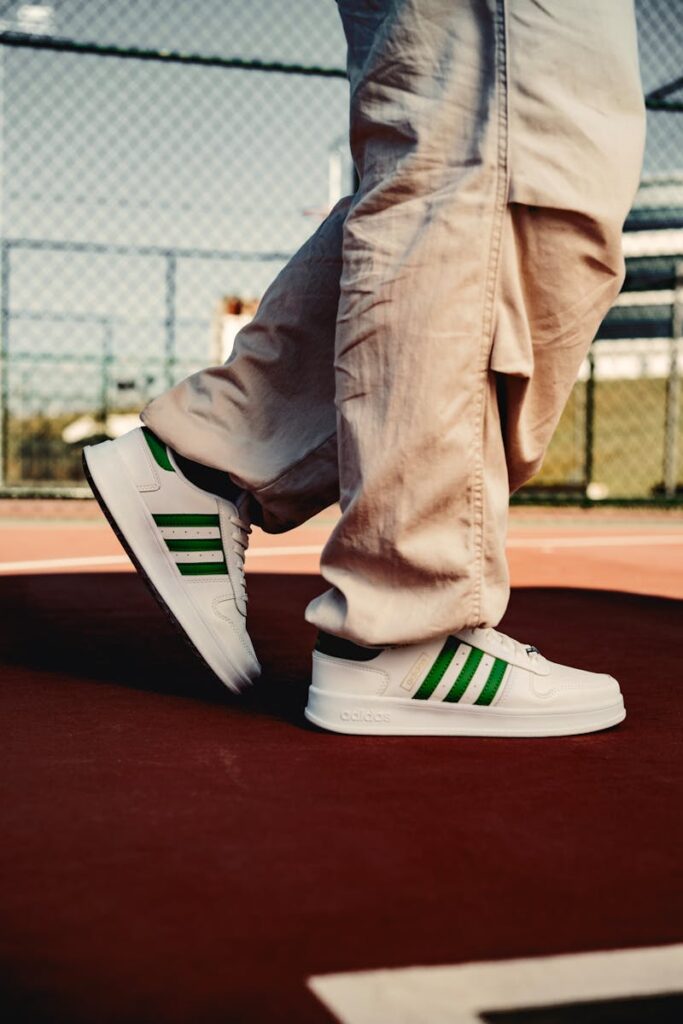 Close-up of white and green sneakers on a tennis court, capturing urban fashion.