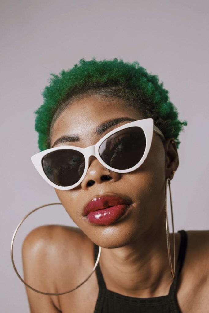 Fashionable woman posing with bold makeup and cat-eye sunglasses.