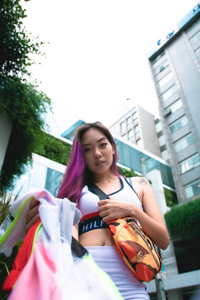 Stylish woman with purple hair in trendy sportswear and fanny pack outdoors.