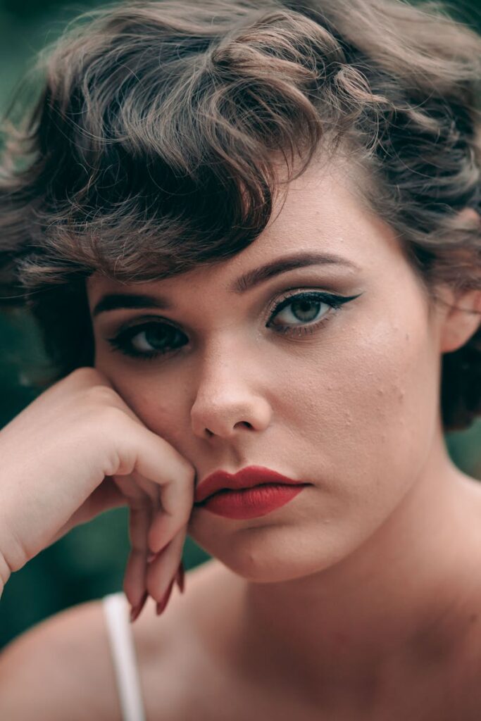 Striking close-up portrait of a woman with short hair and red lipstick, exuding confidence.