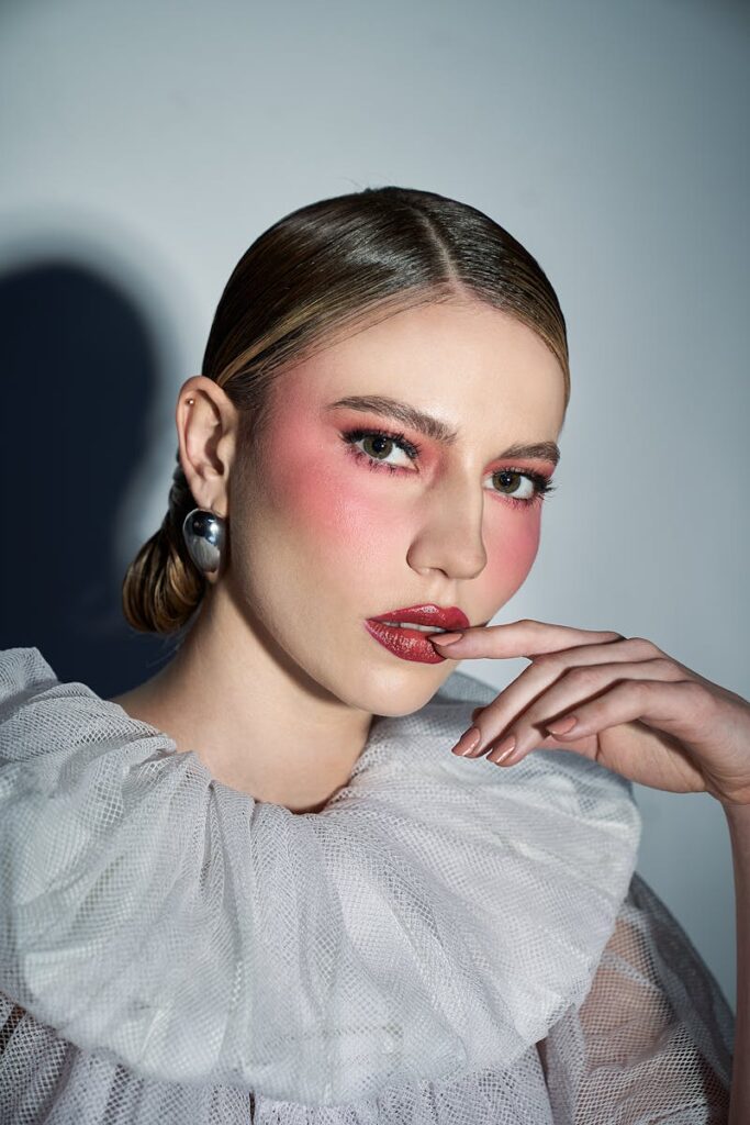 Close-up portrait of a woman in stylish fashion with dramatic makeup and elegant attire.