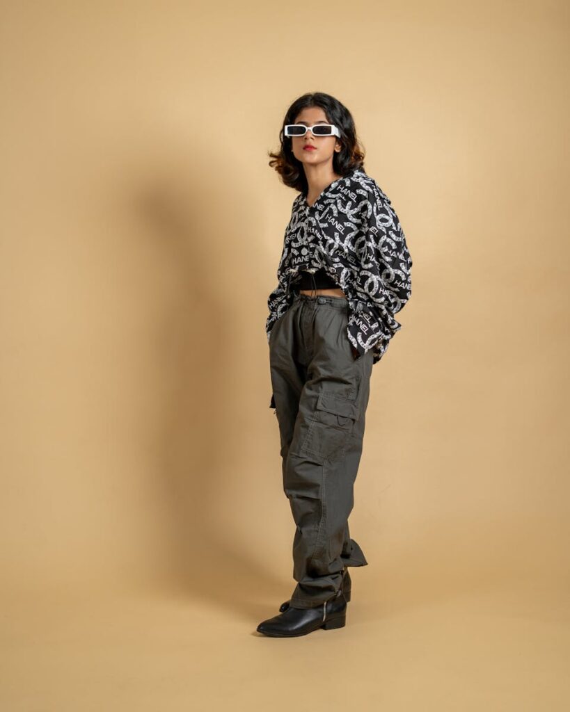 Trendy young woman posing in stylish cargo pants and sunglasses in a studio setting.