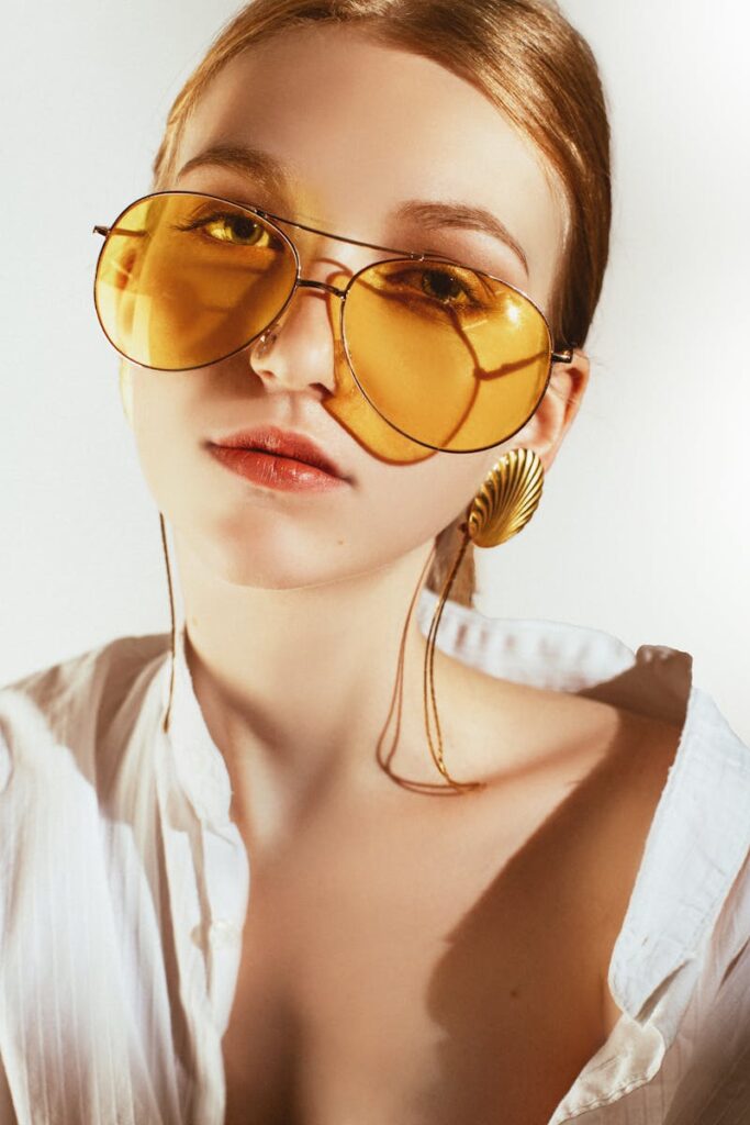 Chic portrait of a woman in yellow sunglasses and statement earrings.