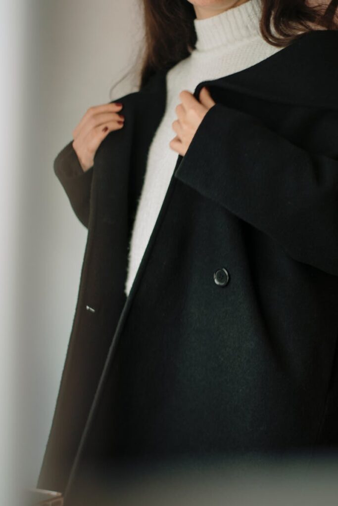 Stylish woman wearing a black coat over a white turtleneck sweater, showcasing winter fashion elegance.