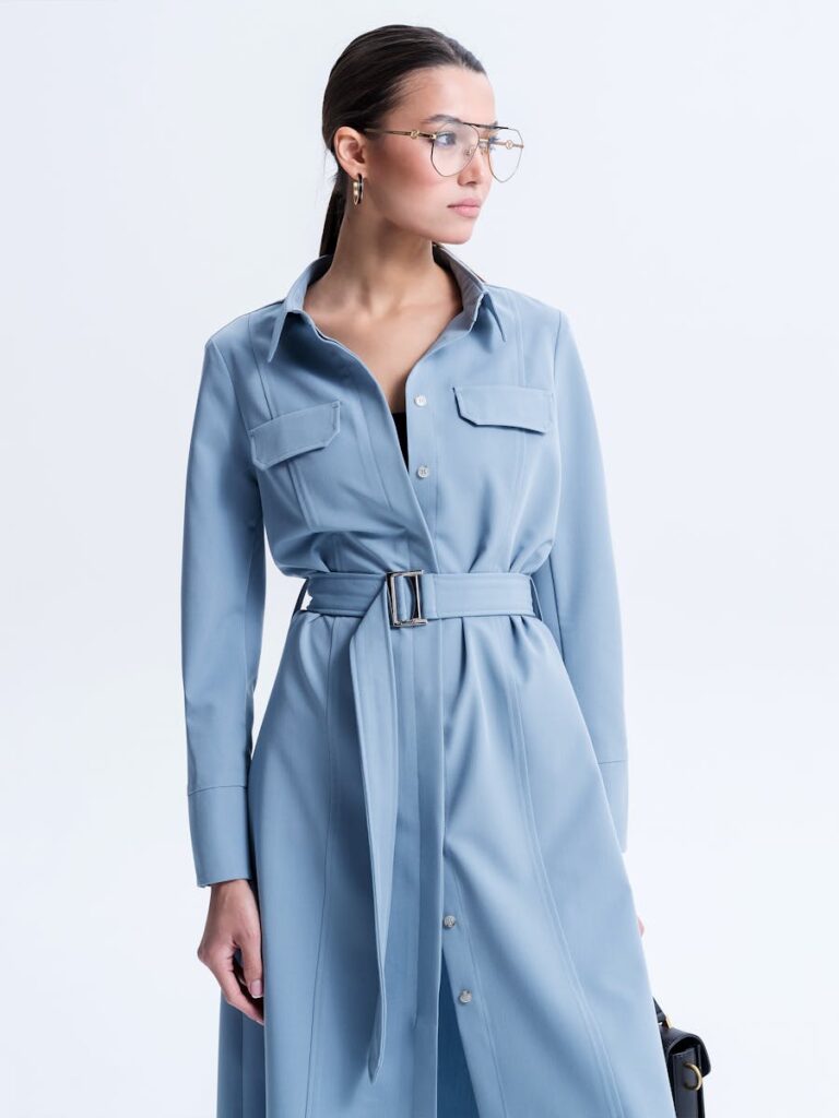 Portrait of a stylish woman in a blue dress and eyeglasses, exuding elegance and sophistication.