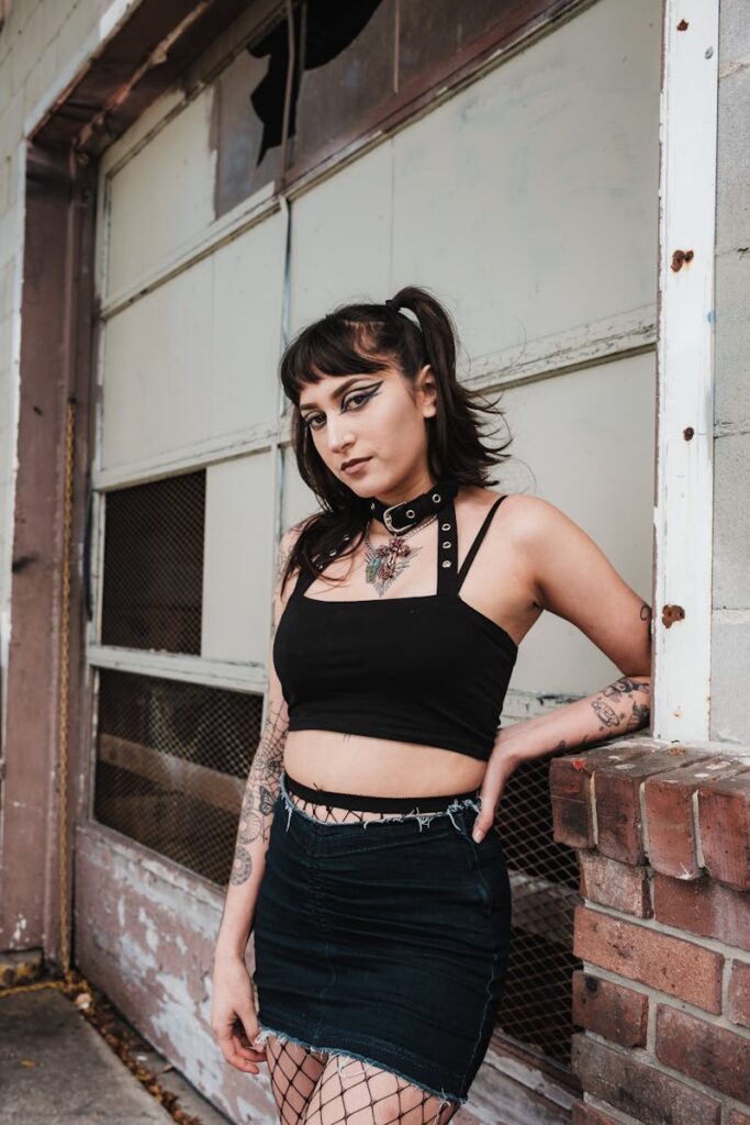 Gothic fashion model in an urban setting with crop top and skirt.