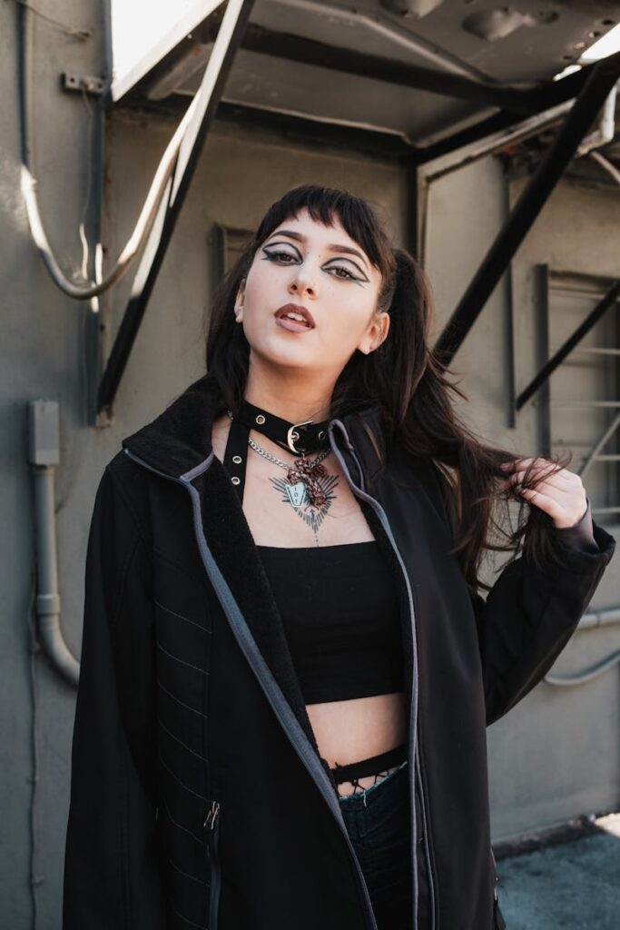 Urban fashion portrait of a stylish woman with gothic makeup and black outfit, showing bold modern style.