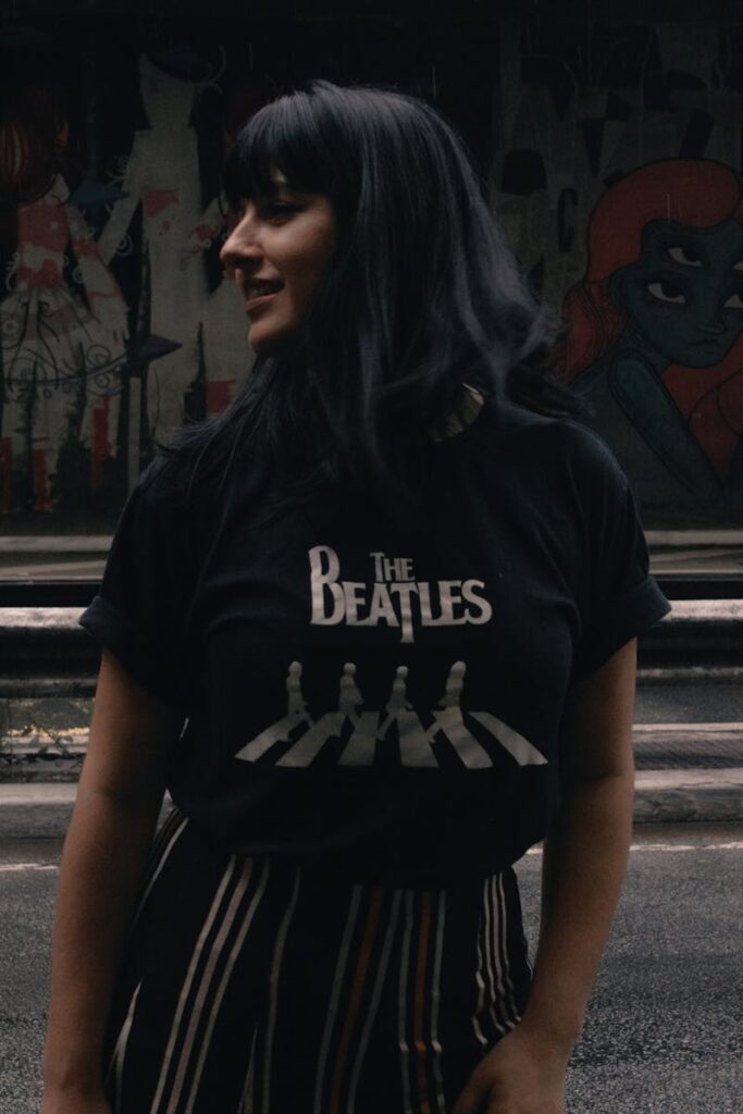 Casual portrait of a woman outdoors wearing a Beatles shirt, conveying retro style.