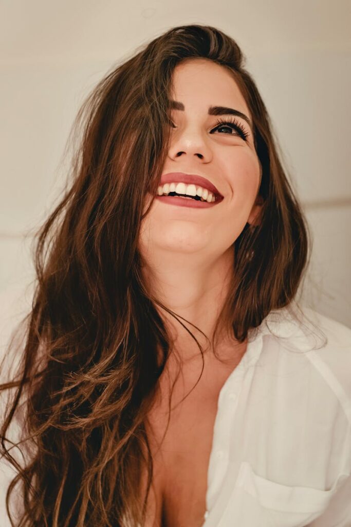 Portrait of a happy woman with long brunette hair and elegant style, expressing joy.