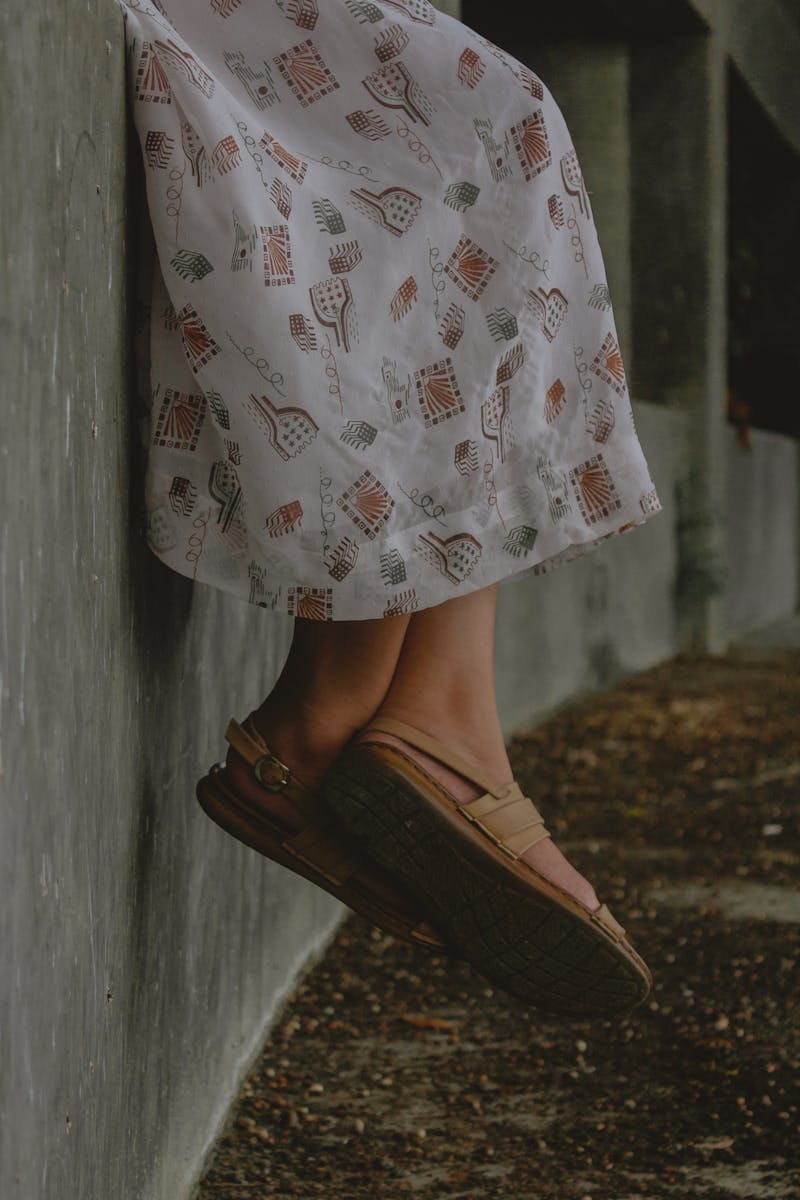 Close-up of a woman's feet in sandals against a textured wall, showcasing style.