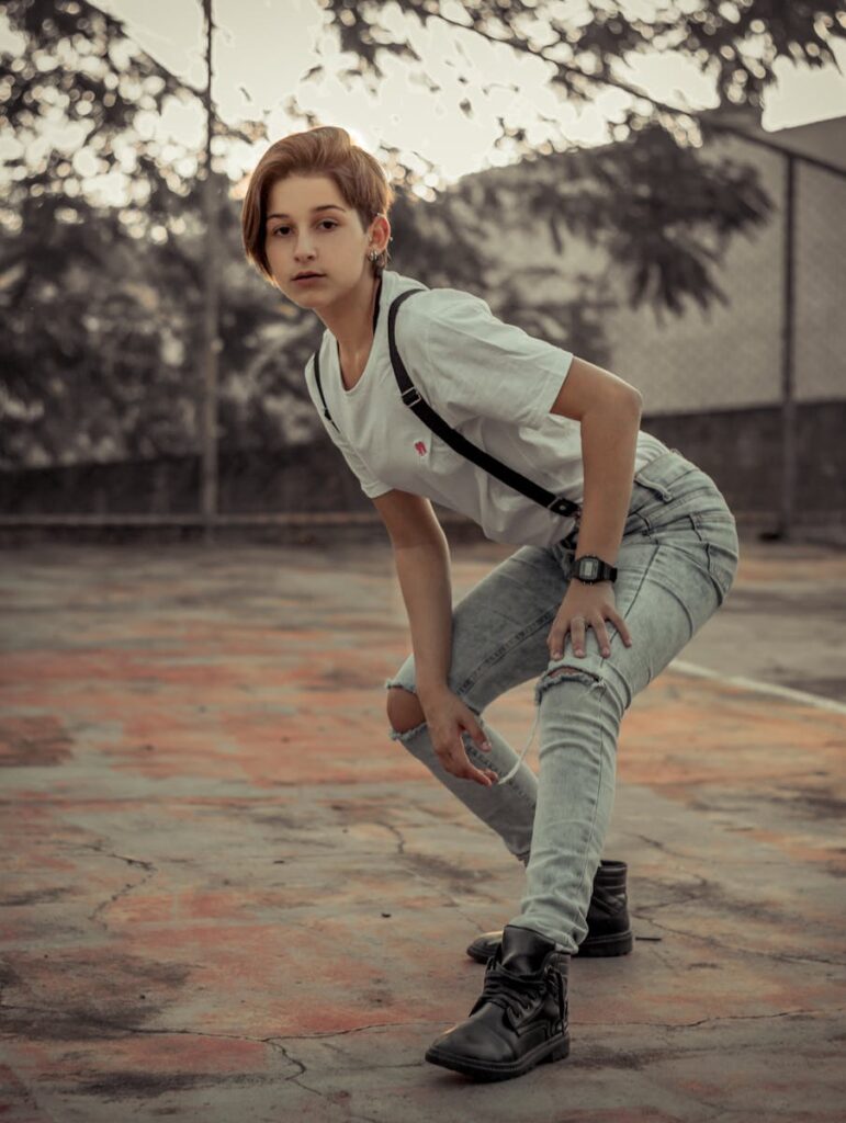 A woman in casual wear, posing confidently on an outdoor basketball court.
