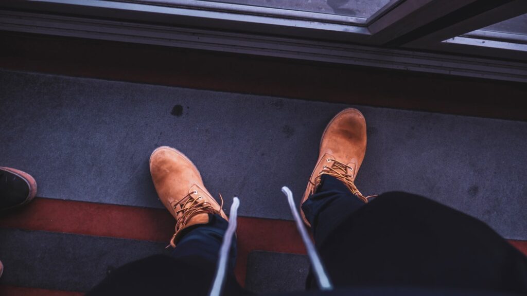 Brown lace-up boots on a geometric floor pattern, perfect for urban fashion concepts.