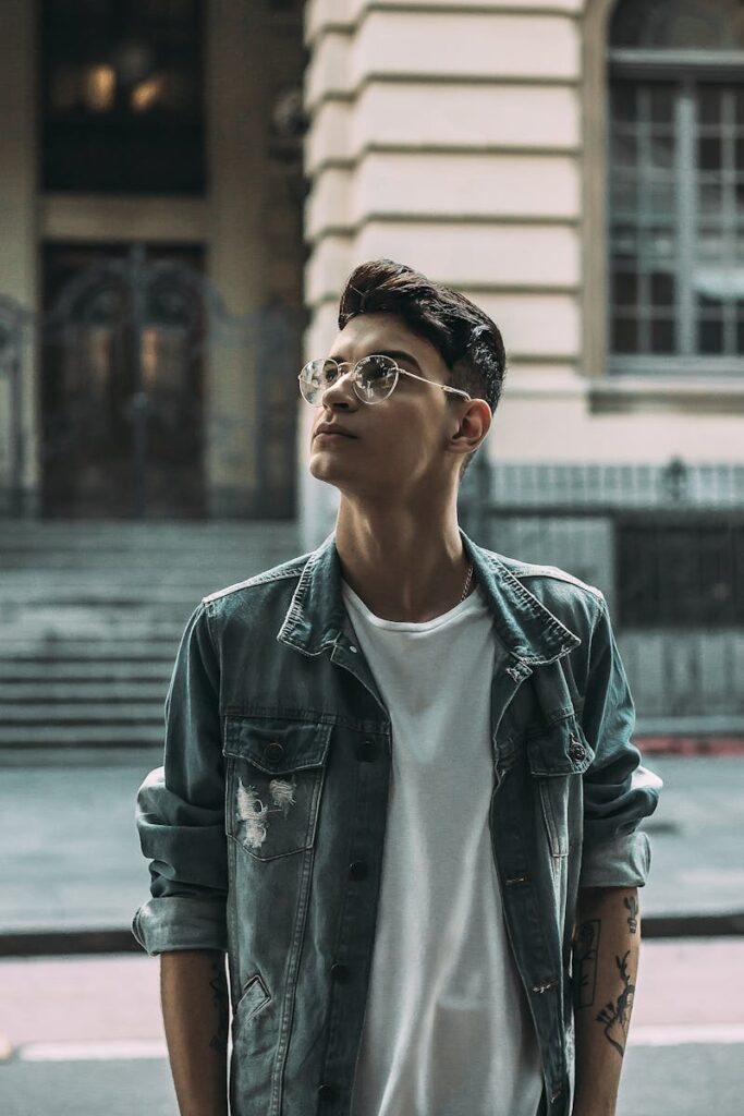 A fashionable man with glasses looks upwards in an urban setting in São Paulo, Brazil.