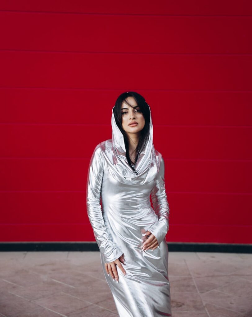 Stylish portrait of a woman in a metallic silver dress against a bold red backdrop.