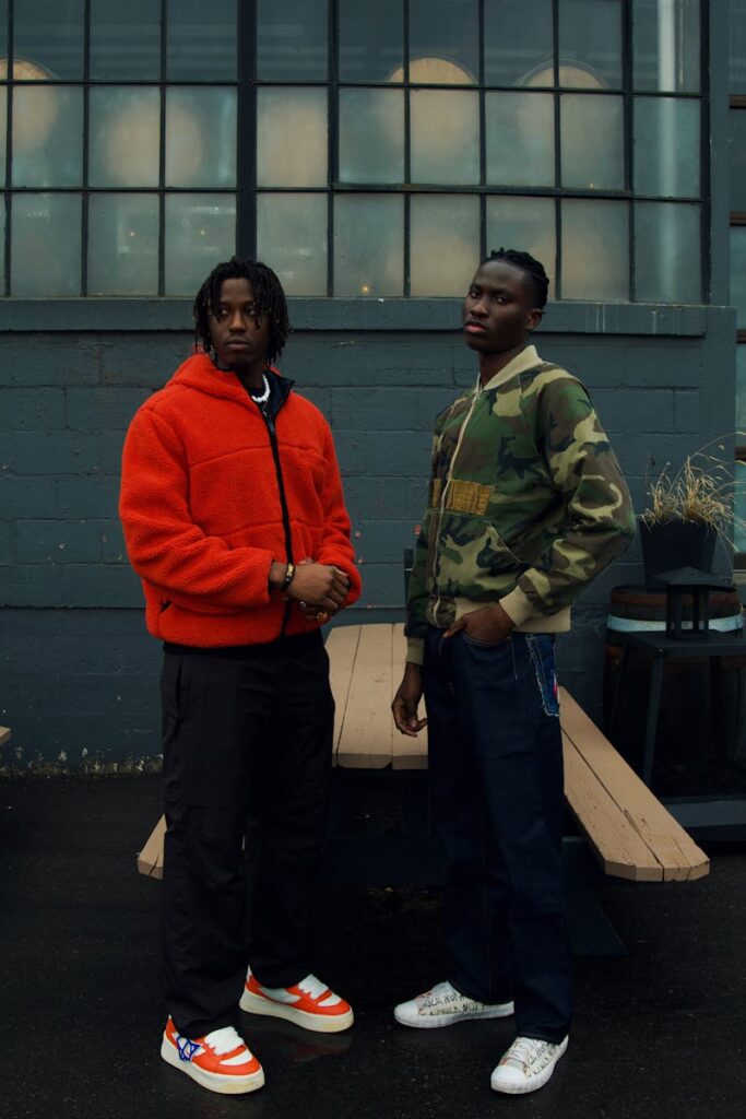 Two adults in streetwear posing outside a building in Toronto. Modern urban fashion and style.