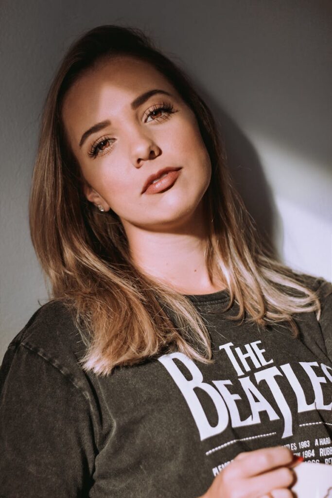 Charming woman posing indoors wearing a The Beatles t-shirt, captured during a photoshoot.