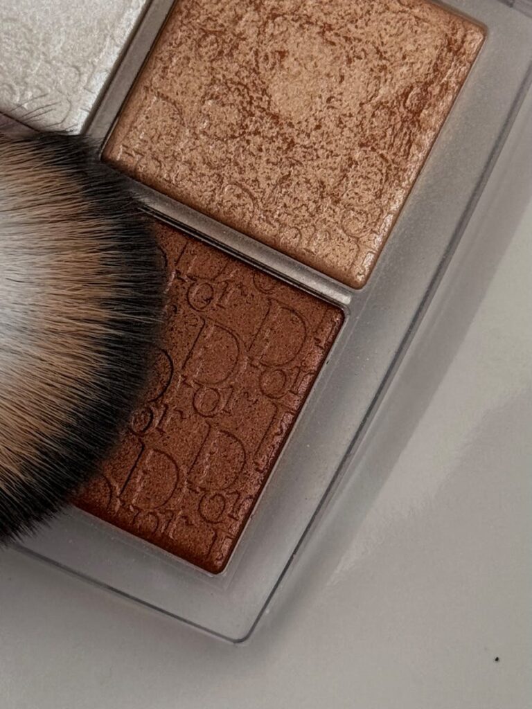 Close-up of a luxury makeup palette and brush, showcasing textures and brown shades.