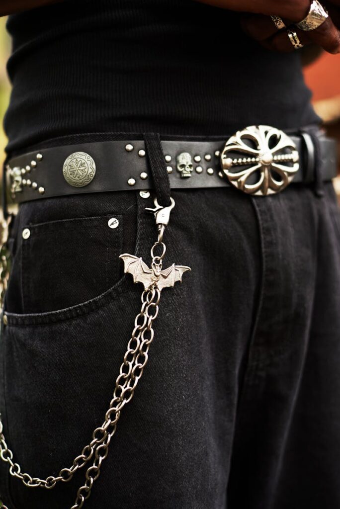 Close-up of a gothic-style belt with silver accessories, chains, and a bat charm.