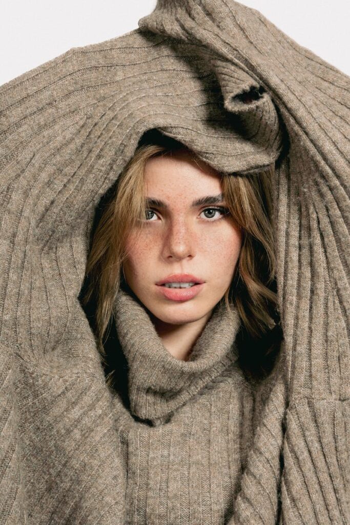 Close-up portrait of a woman framed by a cozy beige sweater for a warm, autumn fashion look.