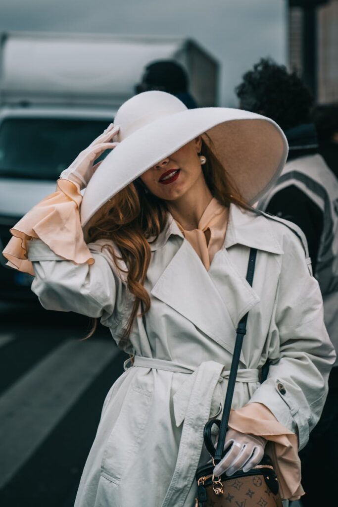 Stylish woman in a large hat at Paris Fashion Week, showcasing chic fashion in a busy urban setting.
