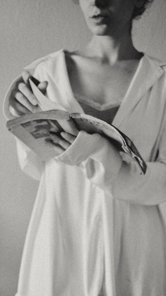 Elegant black and white portrait of a woman reading in soft light, exuding timeless grace.