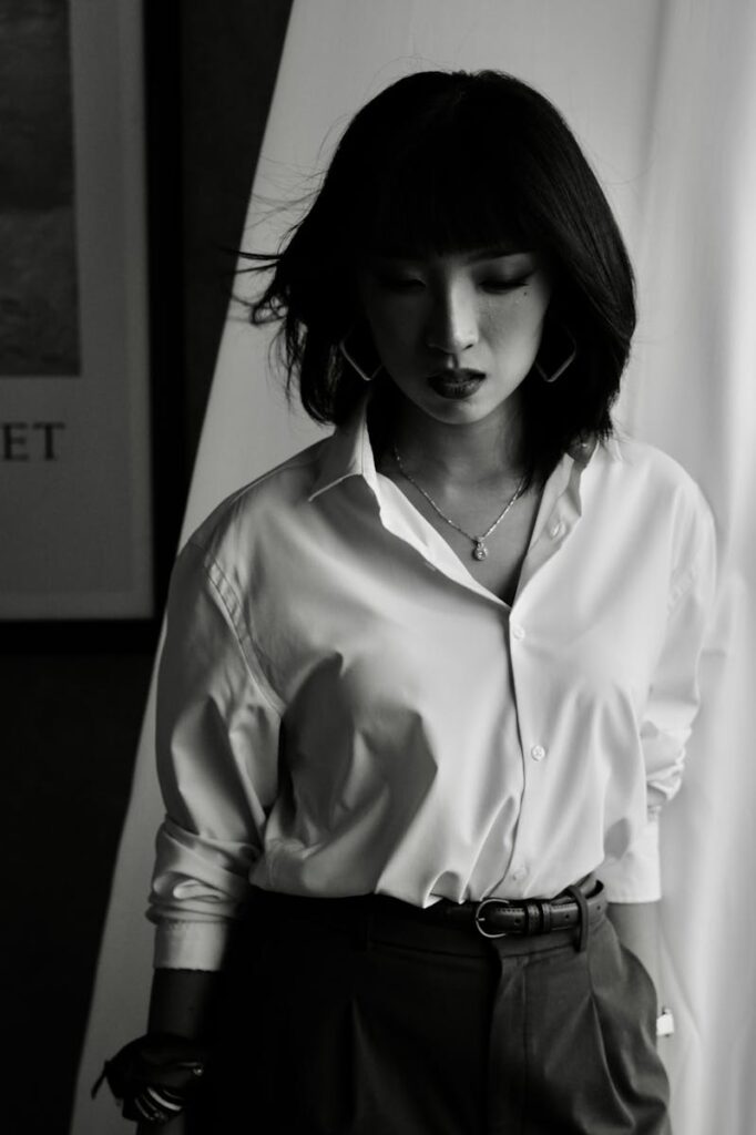 Artistic black and white portrait of a woman in a white shirt indoors.