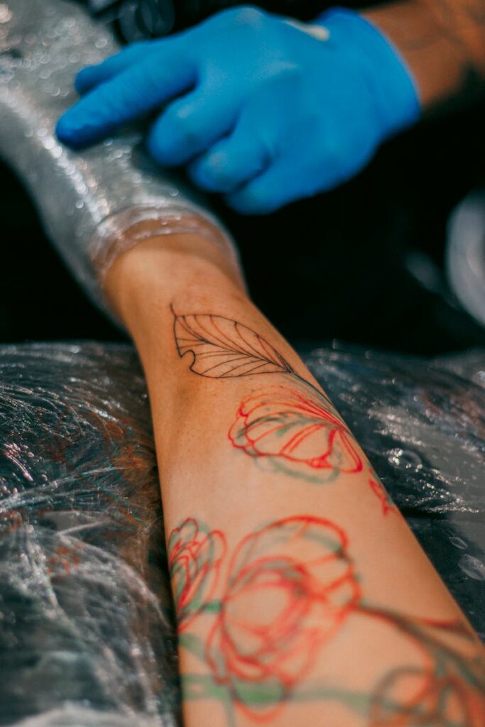 A tattoo artist designs a floral tattoo on a person's arm with precision.