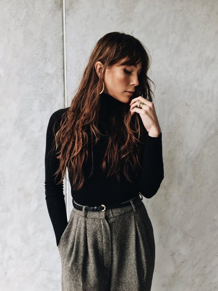 Stylish woman posing in contemporary attire with a minimalist urban background.