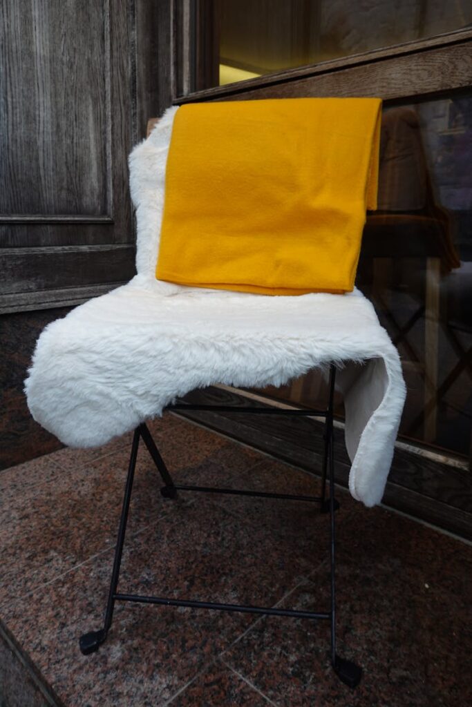 Cozy outdoor seating with a sheep skin chair and warm yellow blanket for winter comfort.