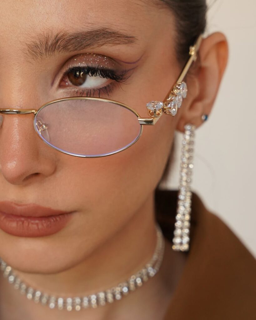 Close-up portrait of a woman with stylish glasses and shimmering jewelry.