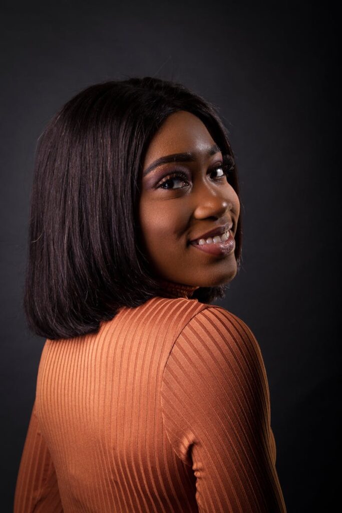 Studio portrait of a beautiful African American woman with a stylish hairstyle, smiling warmly.