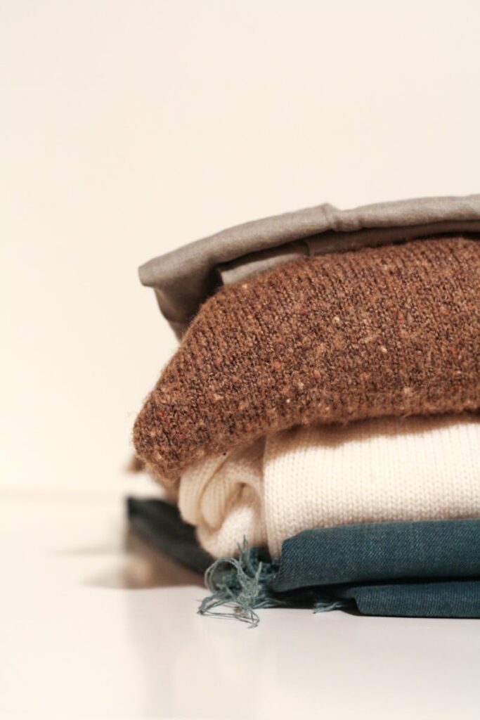 Neatly folded stack of cozy sweaters showcasing textures and layers.