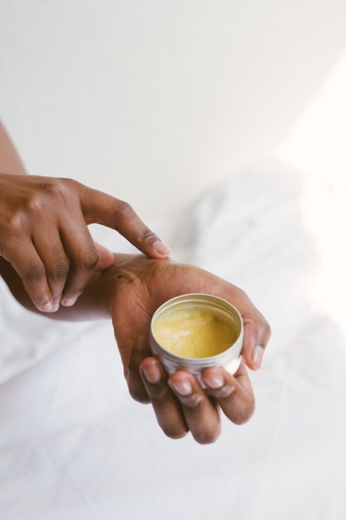 Close-up of a hand applying natural skincare cream, emphasizing self-care and holistic health.