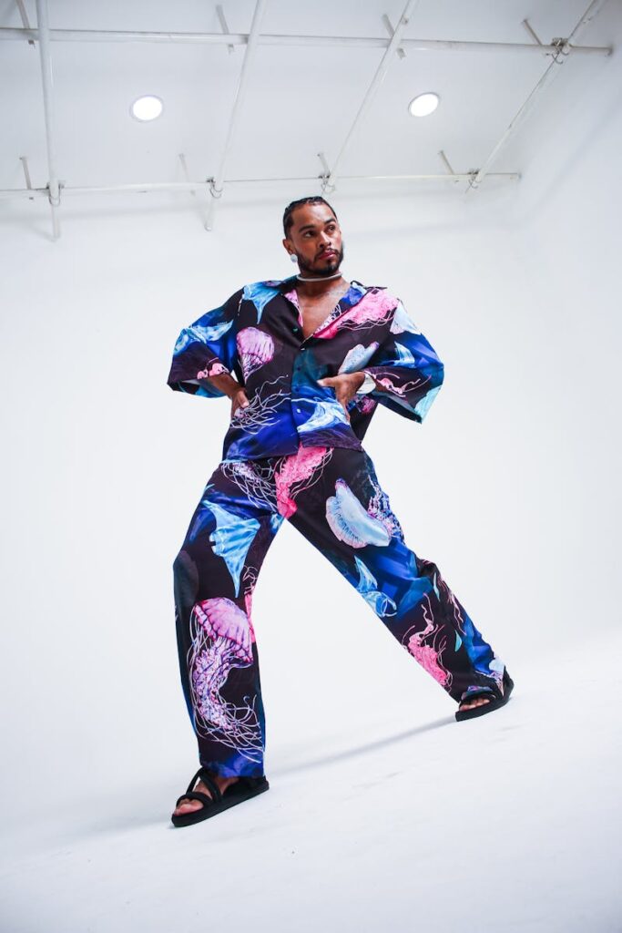 Stylish man in vibrant jellyfish print suit striking a pose in a modern studio setting.