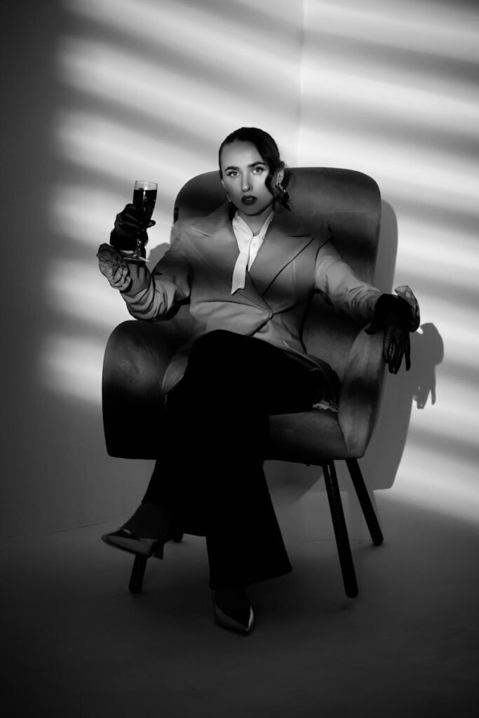 Dramatic black and white portrait of a stylish woman holding a glass.