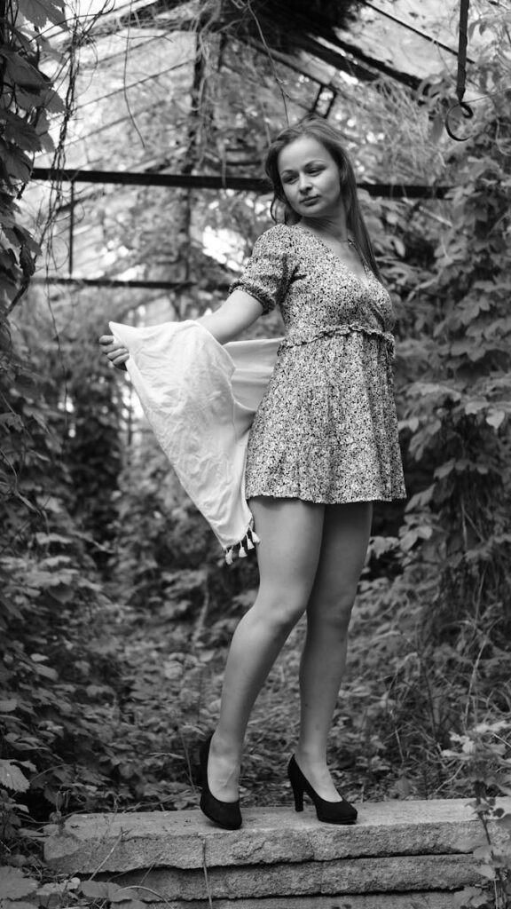 Artistic black and white portrait of a woman in a garden, showing elegance and style.