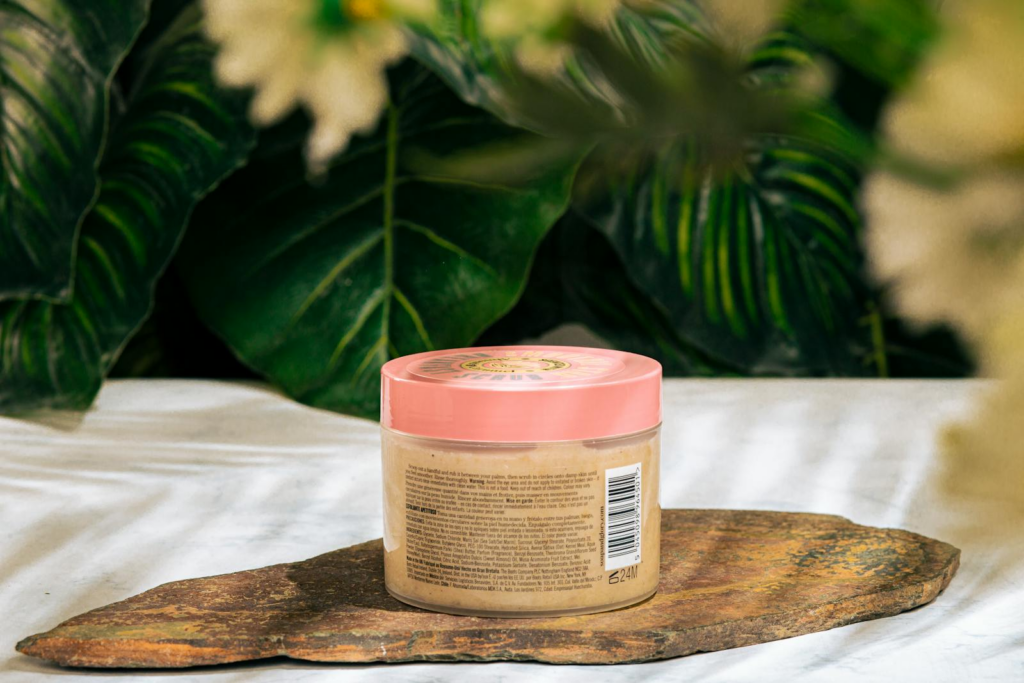 Organic skincare product jar set against lush green leaves for natural beauty theme.