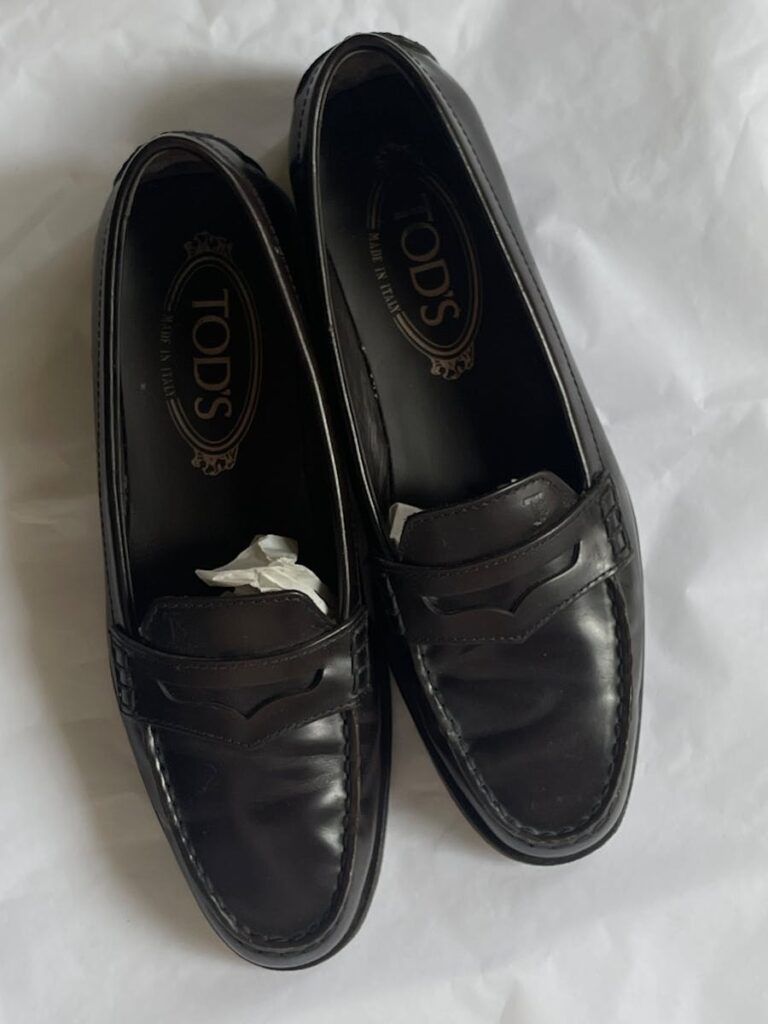 Pair of classic black leather loafers on white background.
