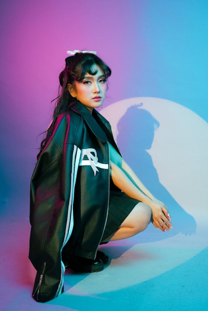 Artistic portrait of a young woman in stylish attire with vibrant colored lighting.