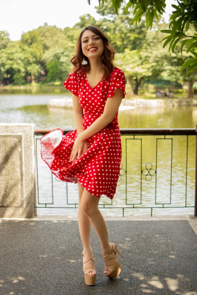 Happy woman in red polka dot dress enjoying a sunny day by the lake.