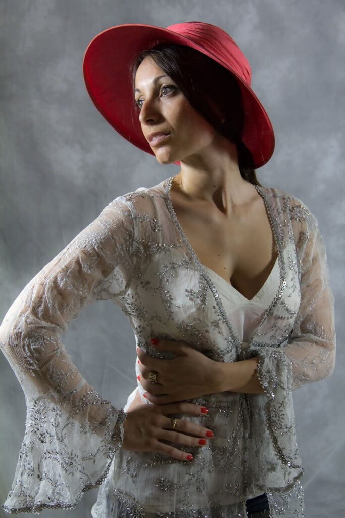 Portrait of a woman in a red hat and sheer lace top, exuding elegance and style.