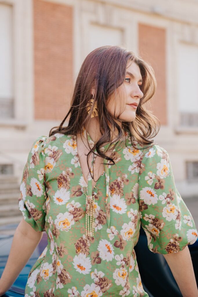Fashionable woman in a floral dress enjoying a sunny day outside.