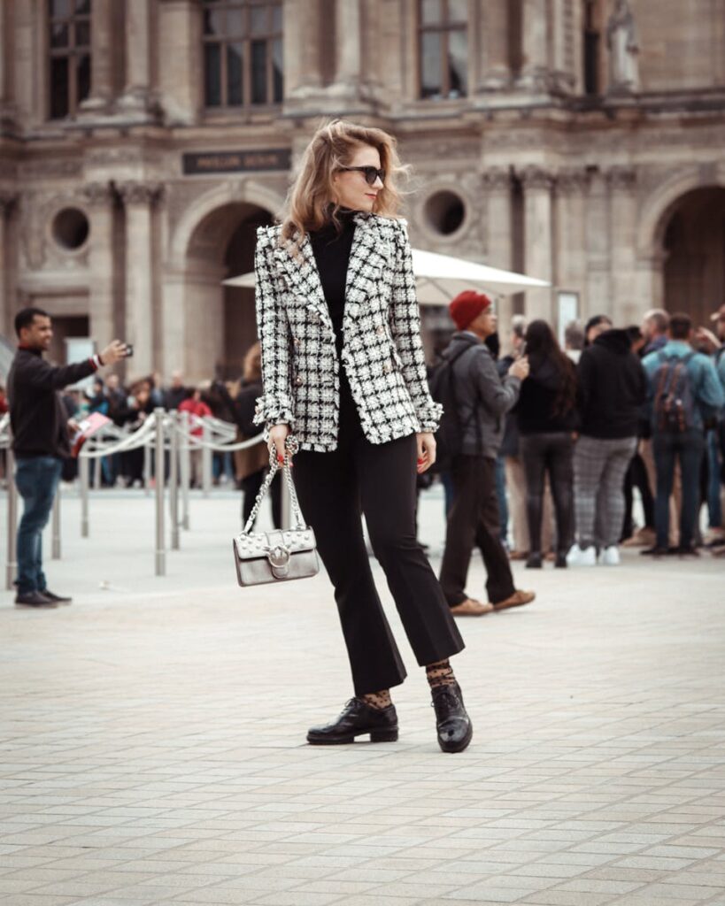 Chic woman poses stylishly in a busy urban area, showcasing modern fashion.