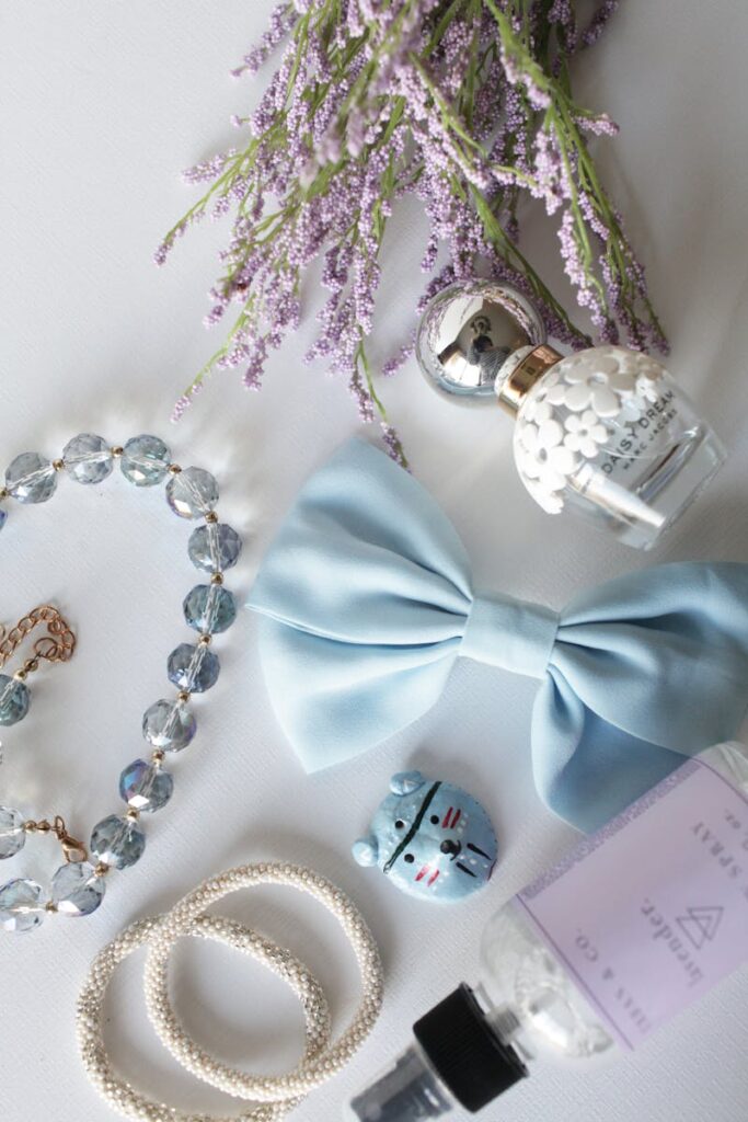 Flat lay of lavender, bow, jewelry, and perfume creating an elegant arrangement on a white background.