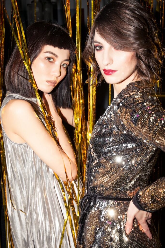 Elegant women in shiny dresses enjoying a night out with gold decorations.
