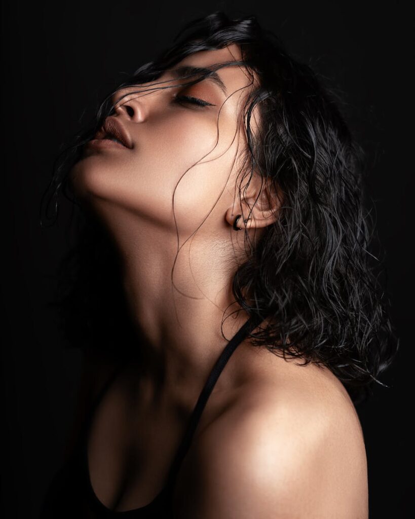 A striking studio portrait of a woman with short black hair against a dark background.