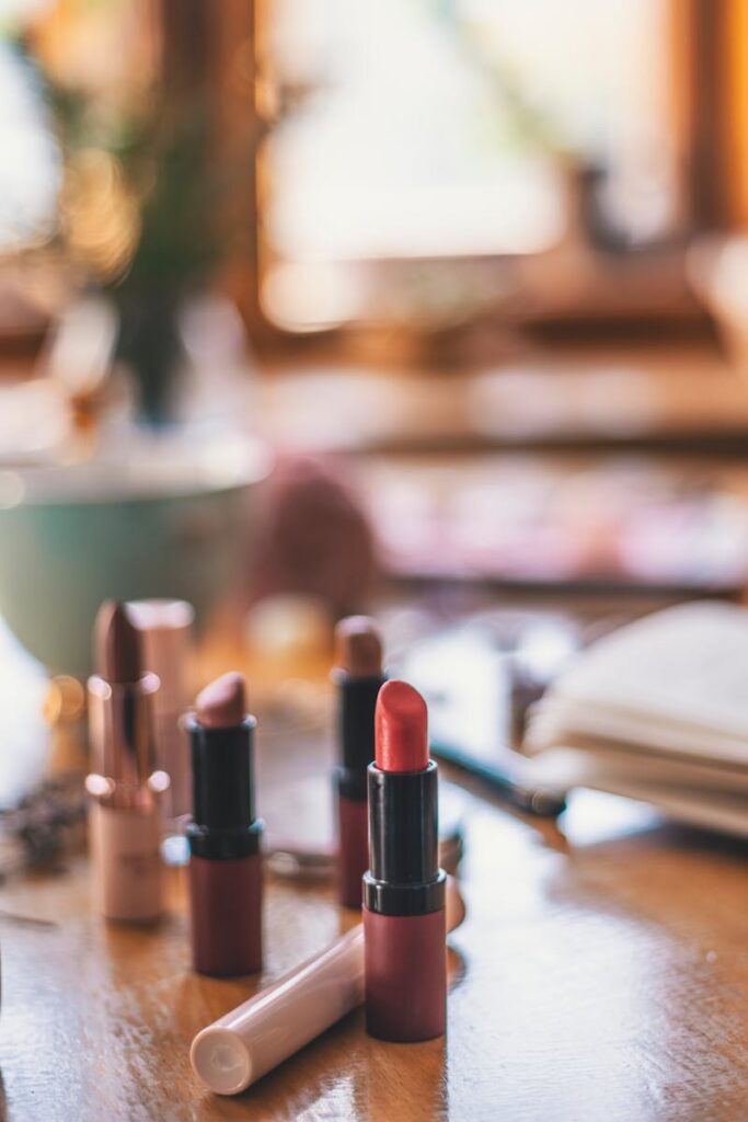 A close-up view of various lipsticks on a wooden table with a blurred background, emphasizing warmth and elegance.