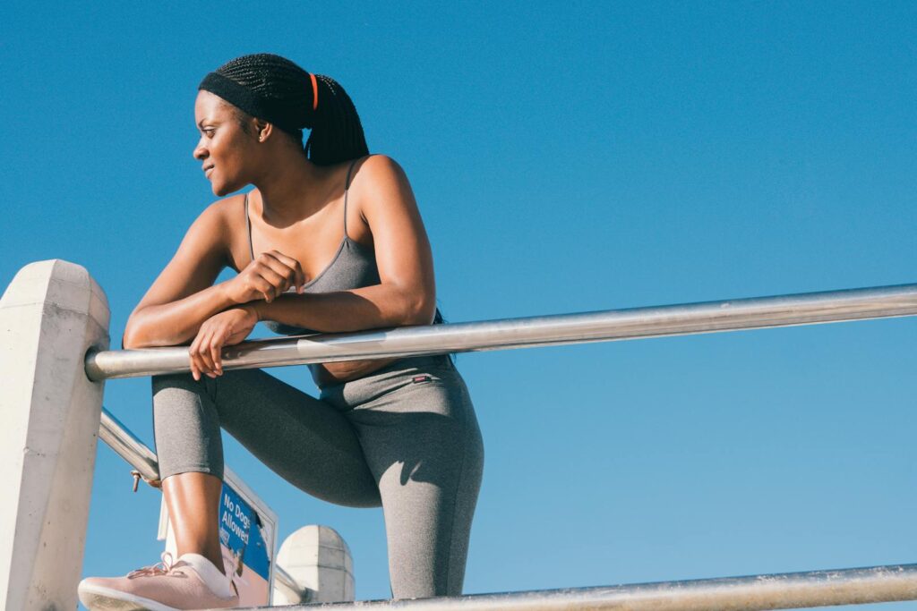 A woman in sportswear enjoys a sunny day outdoors highlighting a healthy lifestyle and fitness.