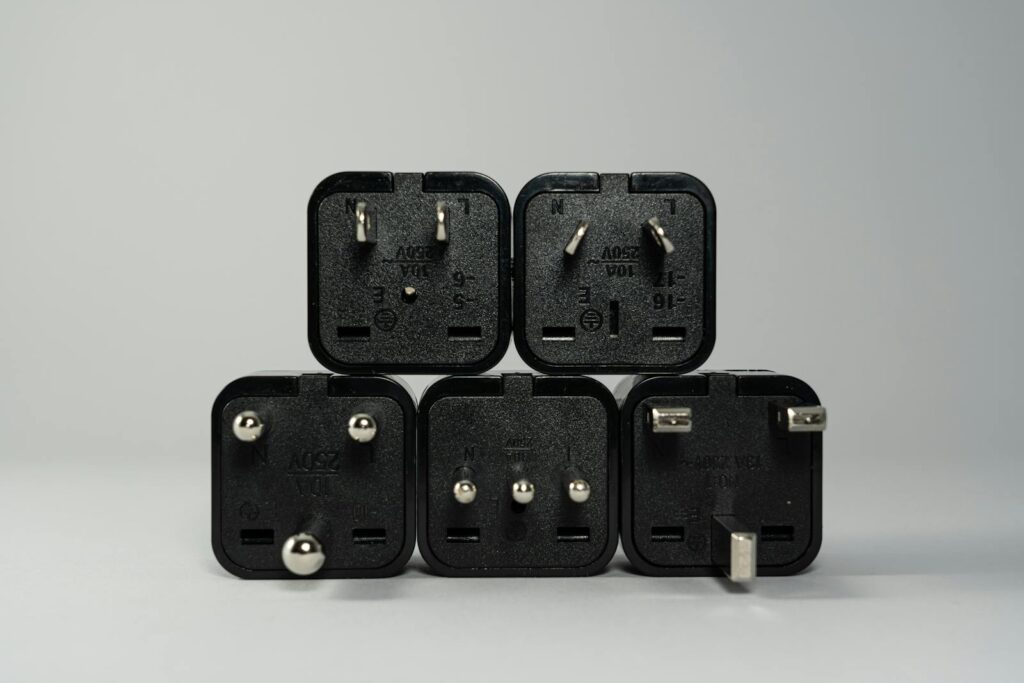 A collection of various black international power plug adapters for global electronics use.